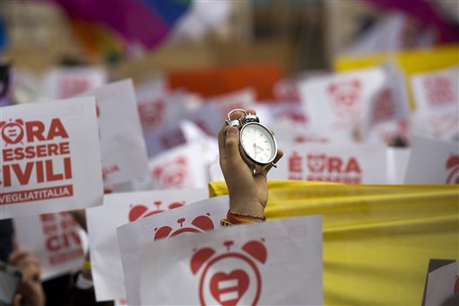 An activist holds up an alarm-clock during a demonstration symbolically  asking Italian lawmakers to wake up and approve a law in favor of rights for gay couples, prior to a debate to be opened in Italian parliament to change laws on recognition of rights for same-sex couples, in Rome, Saturday, Jan. 23, 2016. (AP Photo/Andrew Medichini)