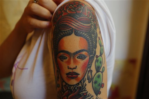 In this Feb. 3, 2016 photo, Dione Lugones shows off her tattoo in the likeness of Mexican artist Frida Kahlo, at La Marca, or The Brand tattoo parlor in Havana, Cuba. Skin art is on the rebound in Cuba, with hundreds of tattoo parlors operating largely unmolested across the country. The socialist revolution drove tattooing underground, with health inspectors and police raiding studios seen as health hazards and vestiges of capitalist immorality. (AP Photo/Desmond Boylan)
