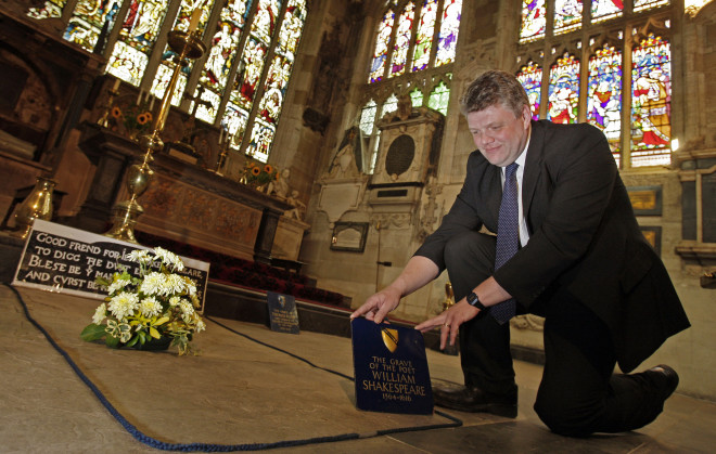 FILE - In this Monday, Sept. 21, 2009 file photo, Head Verger Jon Ormrod tends to the grave of William Shakespeare in the Chancel of Holy Trinity Church in Stratford Upon Avon, England. Archeologists who scanned the grave of William Shakespeare say they have made a startling discovery: His skull appears to be missing. The researchers used ground-penetrating radar to explore beneath the playwright's tomb in Stratford-upon-Avon's Holy Trinity Church. Kevin Colls, who led the study, said the team found "an odd disturbance at the head end." He said Thursday, March 24, 2016 the finding lends support to a claim that the Bard's skull was stolen by grave-robbers in the 18th century.  (AP Photo/Kirsty Wigglesworth, file)