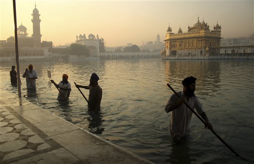 In this Nov. 17, 2013, file photo, Indian Sikh devotees clean the tank early in the morning at the Golden Temple, on the birth anniversary of Guru Nanak, the first Sikh Guru in Amritsar, India. The chronic air pollution blanketing much of northern India is now threatening the holiest shrine in the Sikh religion, making the once-gleaming walls of the Golden Temple dingy and dull. (AP Photo/Sanjeev Syal, File)