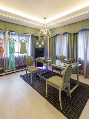 THE DESIGNER’S clothes dangle from steel frames against a neutral backdrop of dove gray curtains and padded walls.