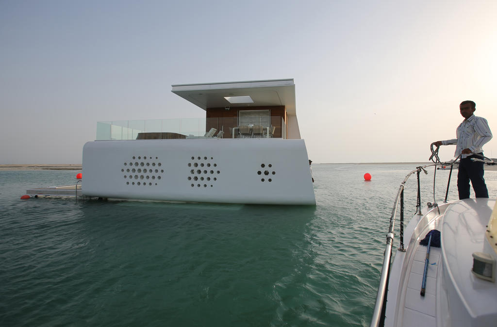 In this Monday, May 9, 2016 photo, a boat which carries clients prepares to dock by a full-scale mock-up of the Floating Seahorse home on the waters of The Dubai World. The Seahorses, part of an ambitious larger hotel development called The Heart of Europe, seeks to attract something that sounds even more grandiose. That's saving The World, as the long-stalled Earth-shaped island project off Dubai's coast is called. (AP Photo/Kamran Jebreili)