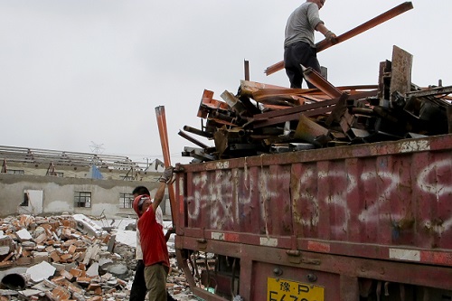 In this June 7, 2016 photo, scrap collectors load materials into a truck on the site of demolished factories in Zhoupu Township in Pudong district of Shanghai. Authorities have evicted hundreds of Shanghai residents and dozens of businesses to clean up the air and make way for the newest Disney theme park, which opens Thursday, June 16. (AP Photo/Paul Traynor)