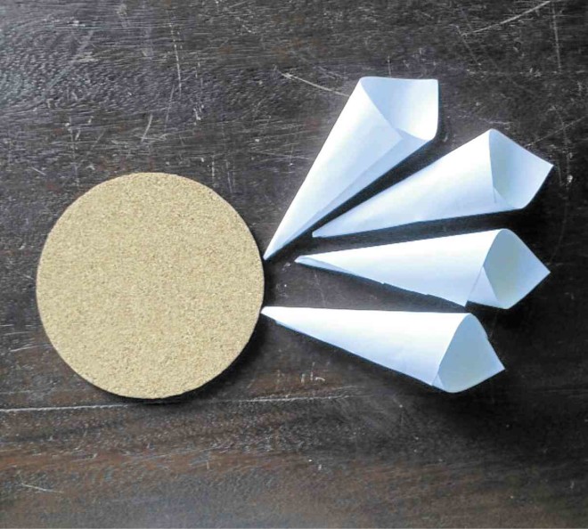CUT SQUARES of paper and roll up like an ice cream cone. You must base the size of your paper cones to the diameter of your base. Our coaster has a diameter of 3.75 inches so our paper squares are 3x3 inches. 