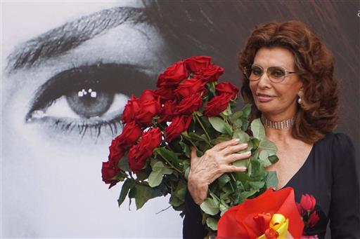 Sophia Loren holds a bunch of red roses as she stands in front a giant portrait of herself after being awarded with the honorary citizenship of Naples, Italy, Saturday, July 9, 2016. AP 