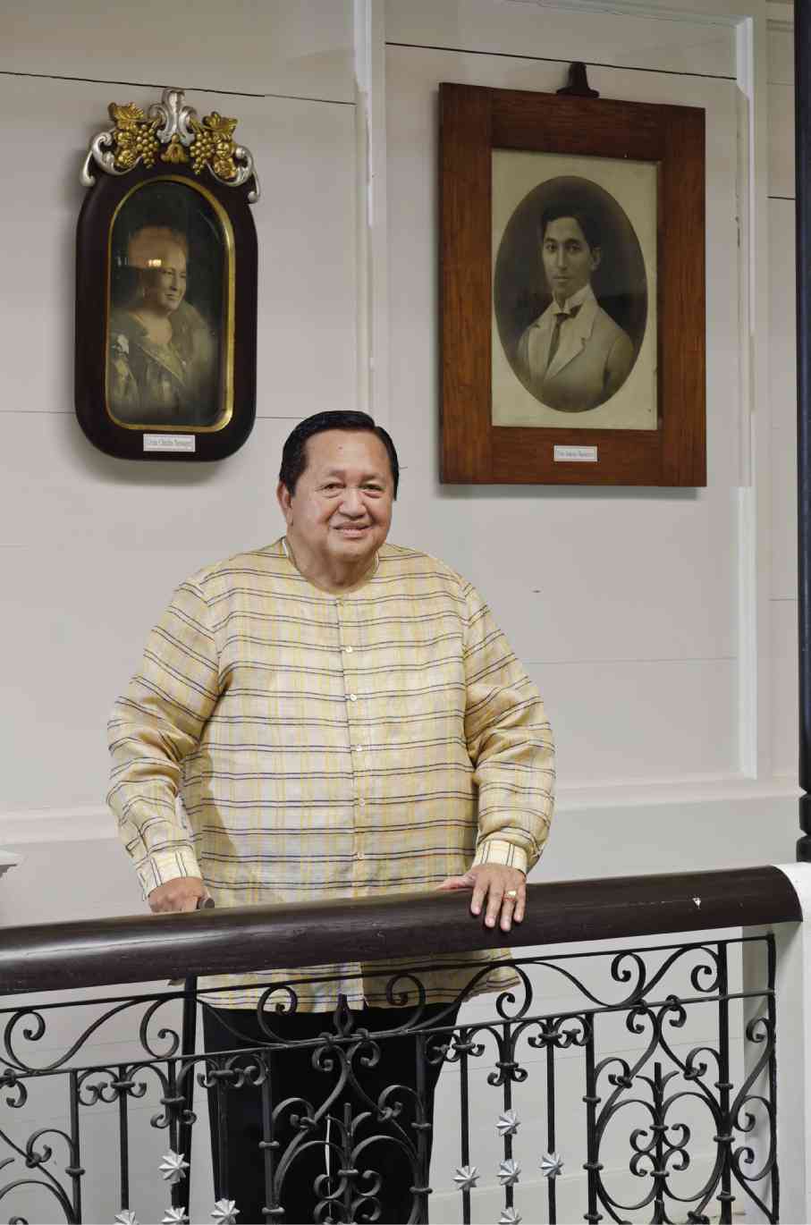 ADOESCUDERO, in Patis Tesoro barong, stands before the portraits of his ancestors.