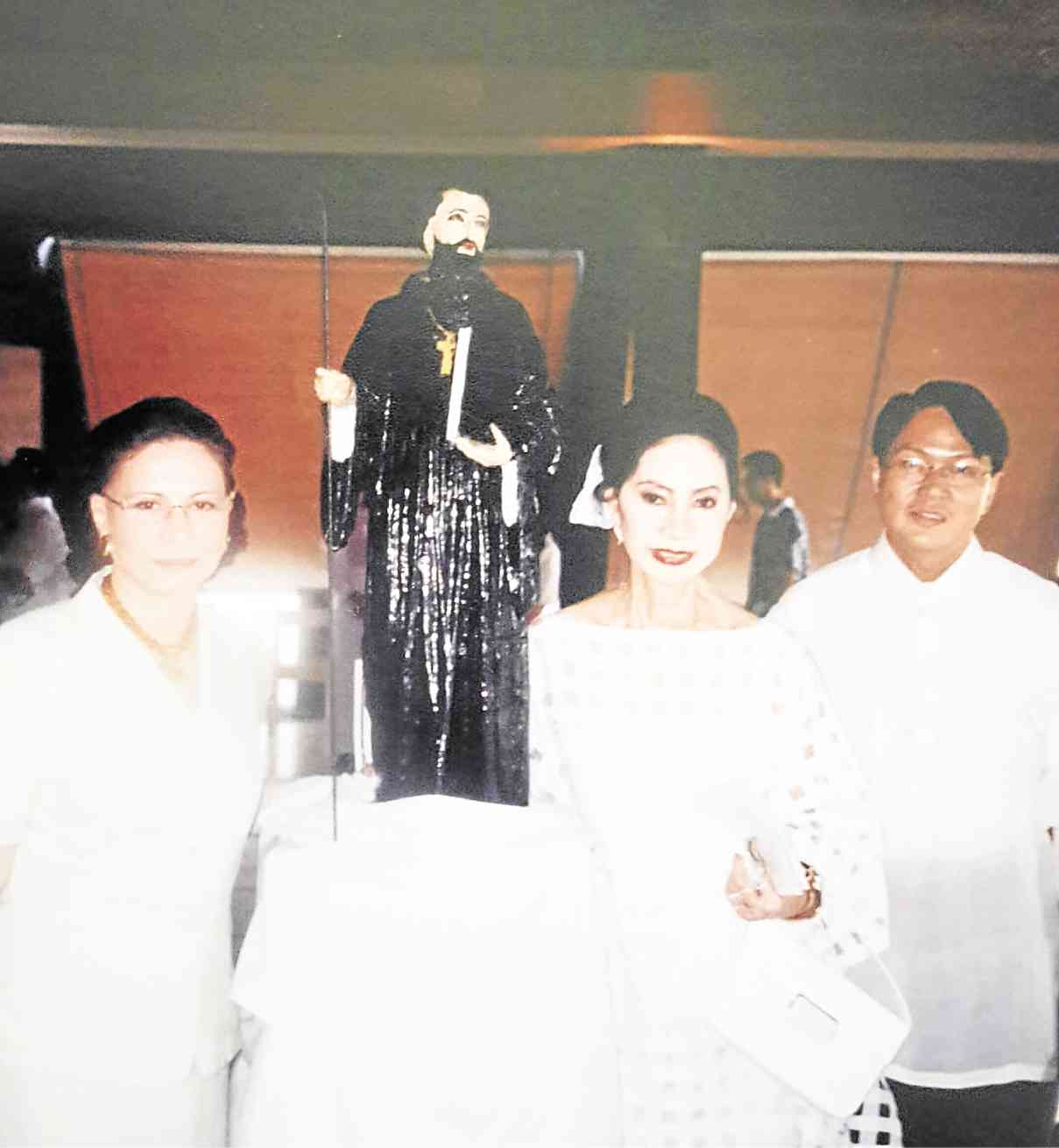 DURING the celebration of the Centennial of Benedictine Presence in the Philippines, Meldy Cojuangco (middle), with Mercy Tuason, who would become ambassador to the Vatican, and fashion designer Bobby Novenario, beside the century-old image of St. Benedict