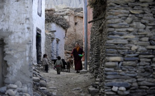 (FILES) This file photograph taken on June 14, 2016 shows a Buddhist monk walking past children in Ghemi Village in Upper Mustang, north-west of Kathmandu.   In Nepal's isolated, high-altitude desert of Upper Mustang, a new road to China is bringing economic transformation to the former Buddhist kingdom, once a centre for trans-Himalayan commerce. / AFP PHOTO / PRAKASH MATHEMA
