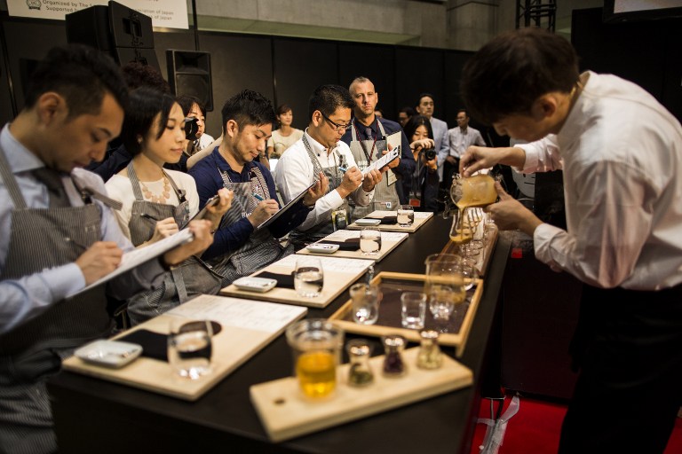 In this photo taken on September 29, 2016, Takayuki Ishitani (R), who won third place in the country's coffee Barista Championship, serves coffee for the jury members during the competition in Tokyo. In a country famous for its tea, the Japanese are increasingly turning to coffee as a quick-fix to help ease the daily grind. Hipster cafés are popping up everywhere, offering exquisitely curated beverages to satisfy even the fussiest of caffeine addicts. / AFP PHOTO / BEHROUZ MEHRI / TO GO WITH AFP STORY JAPAN-LIFESTYLE-COFFEE-CULTURE,FEATURE BY ALASTAIR HIMMER