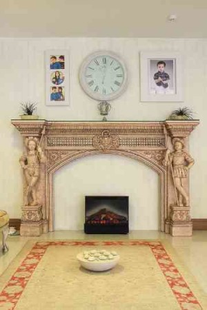 Classically carved mantel with caryatids frames the modern fireplace.