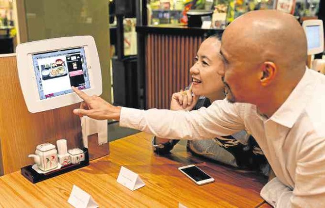 Philippine Tatler’s Mia Borromeo and ABS-CBN Publishing president Ernie Lopez scroll through Yayoi’s interactive menu.