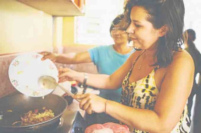 One of the “nanays” teach a guest how to cook a Filipino dish.