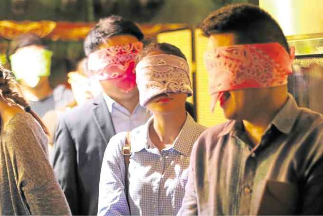 Blindfolded guests being ushered into the dining hall —Nico Belasco/Mackay Green Energy Inc.