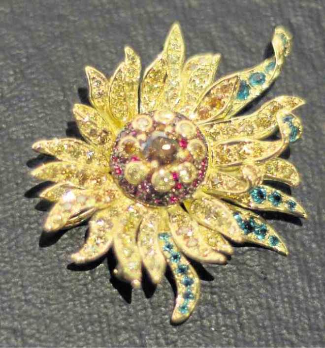 Sunflower brooch pendant has emeralds, rubies, golden and cognac diamonds set in yellow gold.