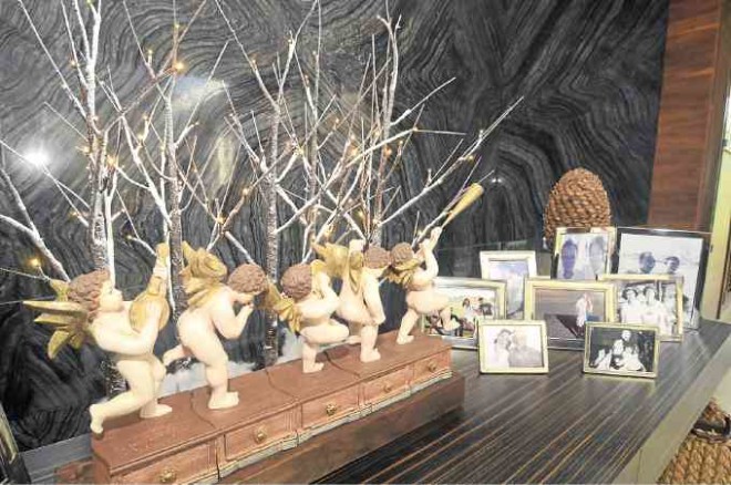 Little holiday ornaments are clustered on the console tables bearing family photos, like these cherubs and artificial twigs with electronic lights.