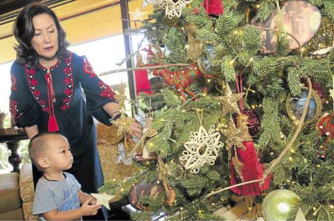 A 12-ft-tall tree trimmedwith gold and red ornaments is the centerpiece of the entertainment room.Nena Tantocowith grandson Bao, daughter Bea’s first child