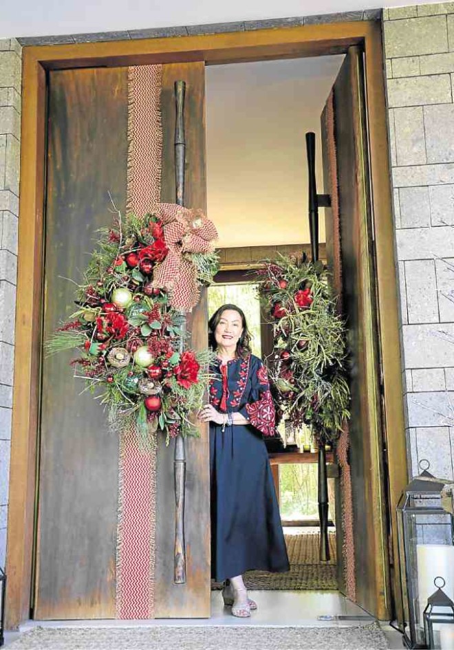 Nena Tantoco welcomes guests at the main entryway of Villa Marina at Sta. Elena, adorned with awreath made of real and artificial leaves, pine needles and red Christmas balls. —PHOTOS BY ARNOLDALMACEN