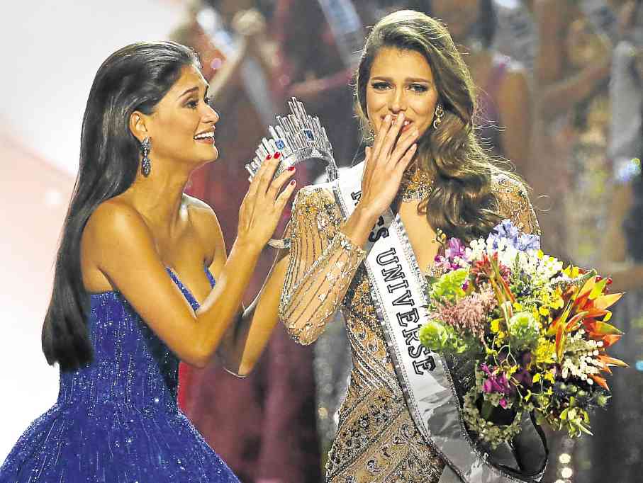 NEW QUEEN Miss Universe Pia Wurtzbach passes the crown to her successor, Iris Mittenaere of France, who bested 85 other candidates in the pageant. —AP