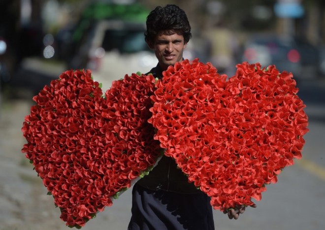 A Pakistani vendor carries heart-shaped bouquets for sale ahead of Valentine's Day along a street in Islamabad on February 13, 2017. / AFP PHOTO / AAMIR QURESHI