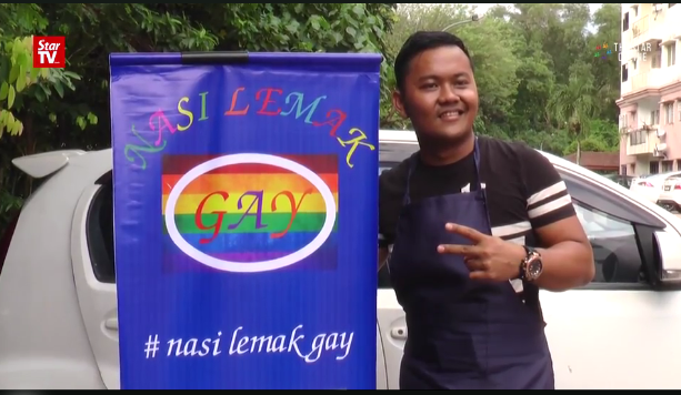 Malaysian businessman Gerai Adi Yusuf poses next to this Nasi Lemak Gay banner. SCREENGRAB FROM THE STAR TV VIDEO/ASIA NEWS NETWORK