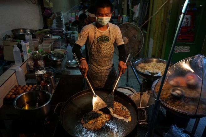 This photo taken on April 17, 2017 shows a man making food at a street stall in the Phrakanong district of Bangkok. Street food stalls will be banned from all of Bangkok's main roads under a clean-up crusade, a city hall official said Tuesday, prompting outcry and anguish in a food-obsessed capital famed for its spicey roadside cuisine.  / AFP PHOTO / LILLIAN SUWANRUMPHA