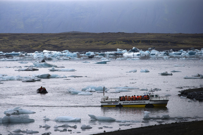 An amphibious vehicle carrying tourists passes blue icebergs in Jokulsarlon, the largest glacier lagoon in Iceland, on July 8, 2014.  AFP FILE PHOTO