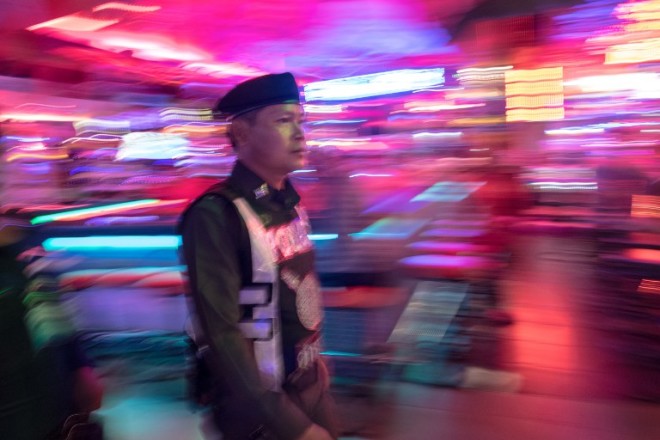 This photo taken on March 29, 2017 shows a Thai policeman patrolling Walking Street in Pattaya. Two hours east of Bangkok, Pattaya's bawdy reputation hails from the Vietnam War era when US GIs partied in their downtime. / AFP PHOTO / Roberto SCHMIDT / TO GO WITH Thailand tourism crime social,FEATURE by Jerome TAYLOR