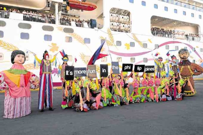 Philippine cultural dance performers greet Superstar Virgo as it docks at home port Manila South Harbour.