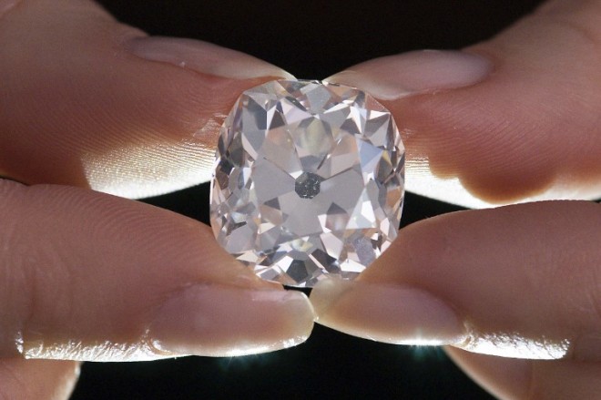 A member of Sotheby's staff poses holding a 26.27 carat, cushion-shaped, white diamond, for sale at Sotheby's auction house in London on May 22, 2017. The large diamond is expected to fetch around 350,000 GBP (405,000 euro; 456,000 USD) at auction 30 years after its owner paid 10 GBP for it at a car boot sale, thinking it was a costume jewel. / AFP PHOTO / Justin TALLIS