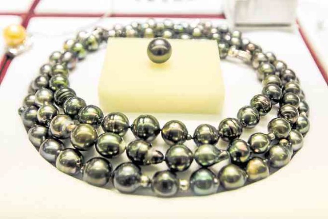 A three-layer choker of black peacock pearls flashes a green tinge when placed under bright lights.