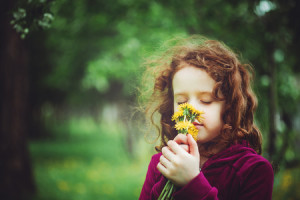 41778927 - little girl closed her eyes and breathes yellow dandelions in the field. background toning to instagram filter.