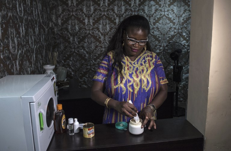 Elizabeth Kobiti, a beauty salon owner, mixes a skin lightening cream on July 13, 2018, in Lagos. Africa is experiencing a massive trend of skin bleaching, also called lightening or whitening, particularly in teenagers and young adults. In Nigeria, 77 per cent of women (more than 60 million people) are using lightening products on a "regular basis", the World Health Organization (WHO) said in 2011. The skin lightening industry has globally grown into a billion dollar industry yet in some places like Africa the practice is still seen as highly controversial, largely unregulated and littered with misconceptions. / AFP PHOTO / STEFAN HEUNIS