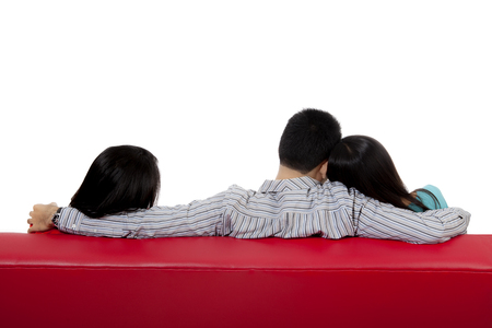 85637893 - back view of man cheating with his friend while hugging his girlfriend wife on the couch