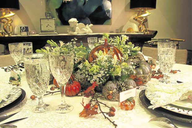 The table centerpiece is a mix of pumpkin sculptures in glass and silver and fresh flowers.