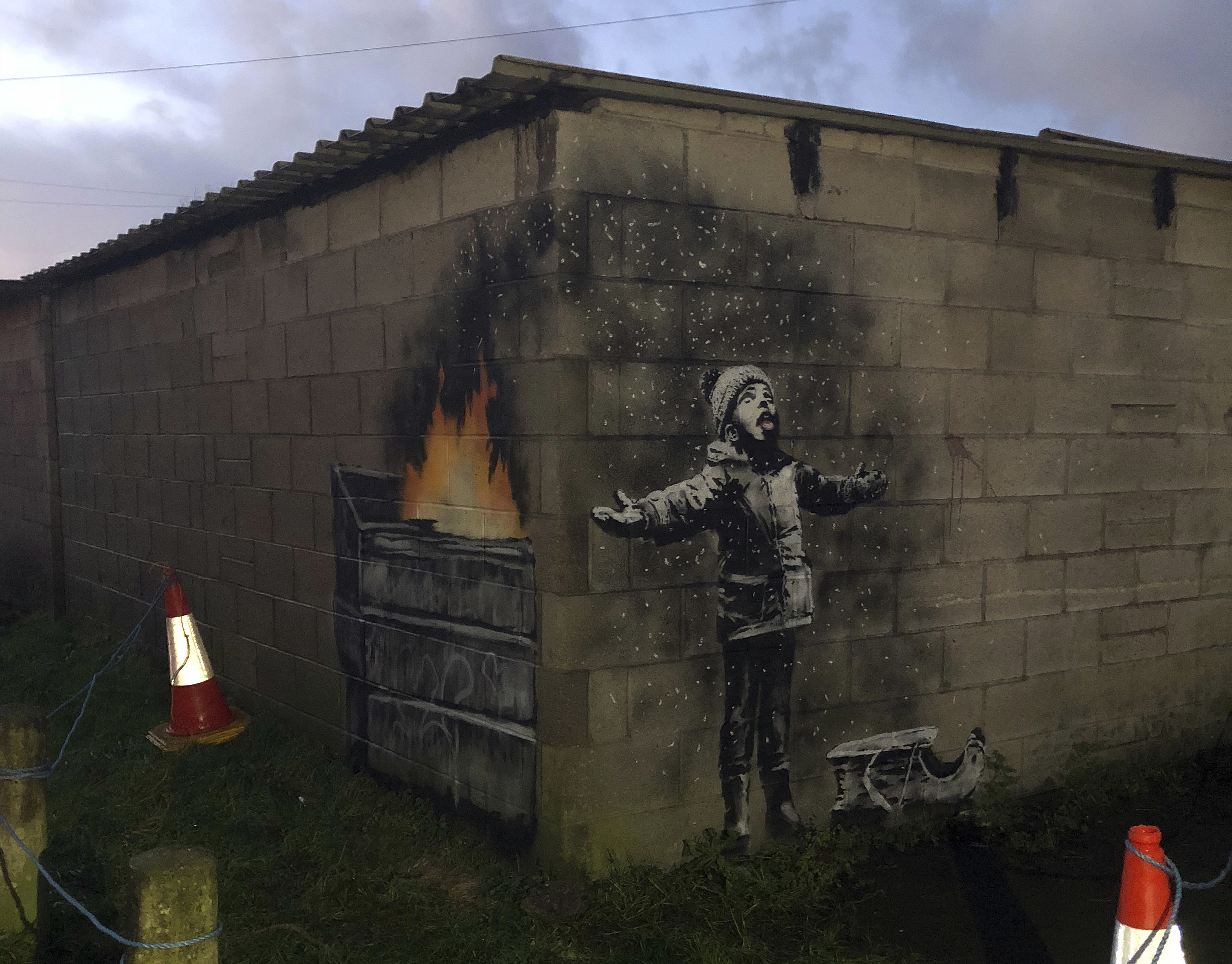 An artwork by street artist and social commentator Banksy is seen on a garage in Port Talbot, Wales, Wednesday Dec. 19, 2018. A video posted to his official Instagram account on Wednesday afternoon had close-ups of the piece, that references the town's air pollution. (Twitter/@RHoneyJones via AP) art