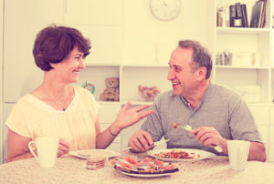 happy smiling mature couple eating lunch together at home