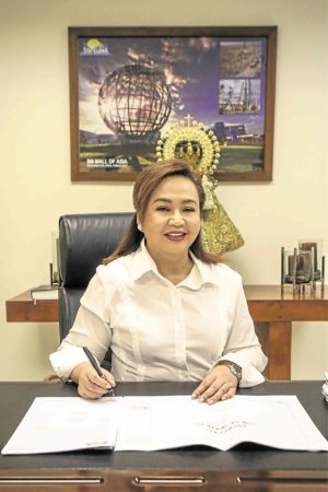 Eduardo at her desk, before the Virgin Mary statue: TheMarian faith and the cutthroat construction businessmake up aworld of contrasts in Eduardo’s life.—PHOTO BY JAM STA. ROSA