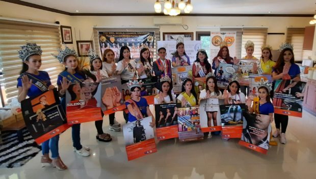 Queens from different pageant organizations show posters about women’s welfare.
