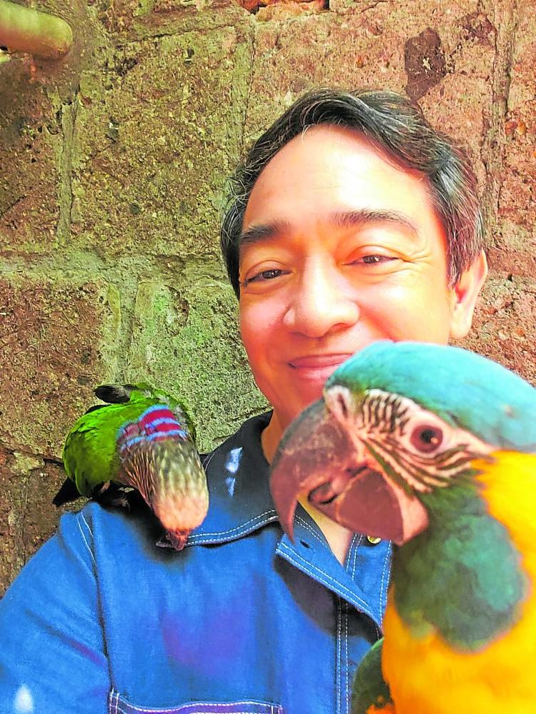 Jimenez with a blue-throated macaw and hawk-headed parrot on his shoulder
