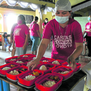 A volunteer prepares meals for distribution.