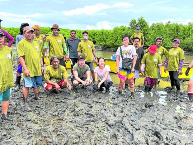 Mangrove Movement founder Uy and vice president Bea Tan with the Noveleta river rangers after a day of planting