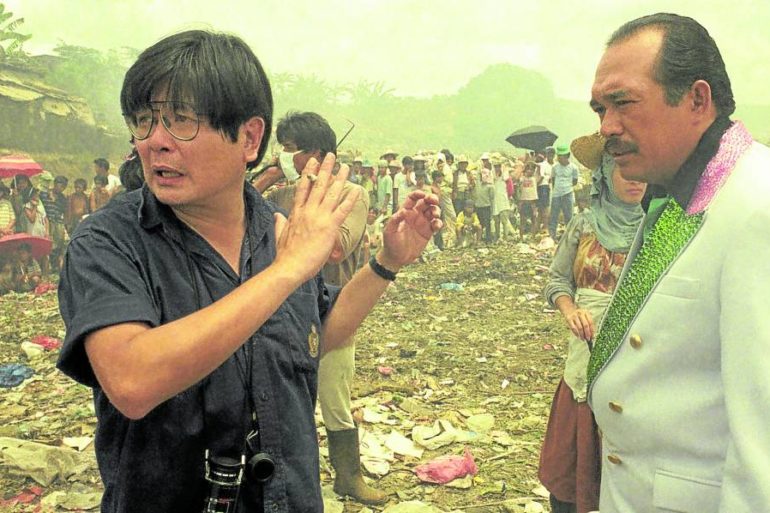 Mike de Leon (left) gives instructions to Johnny Delgado at the Payatas garbage dump for a scene in “Aliwan Paradise.”