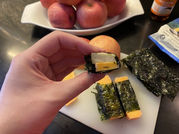 sliced cheese and apples wrapped in a sheet of seasoned seaweed
