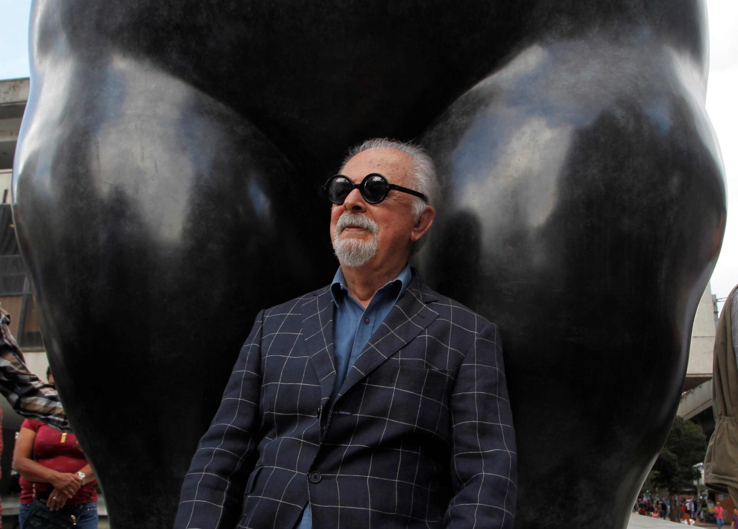 Colombian painter and sculptor Fernando Botero sits underneath one of his sculptures in Medellin