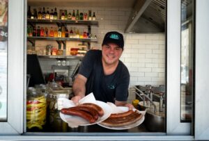 Patrick Bernhardt, employee at Vienna's oldest operating sausage stand 'Wuerstelstand LEO', poses for a photo with plates of sausages in Vienna, Austria on June 18, 2024.