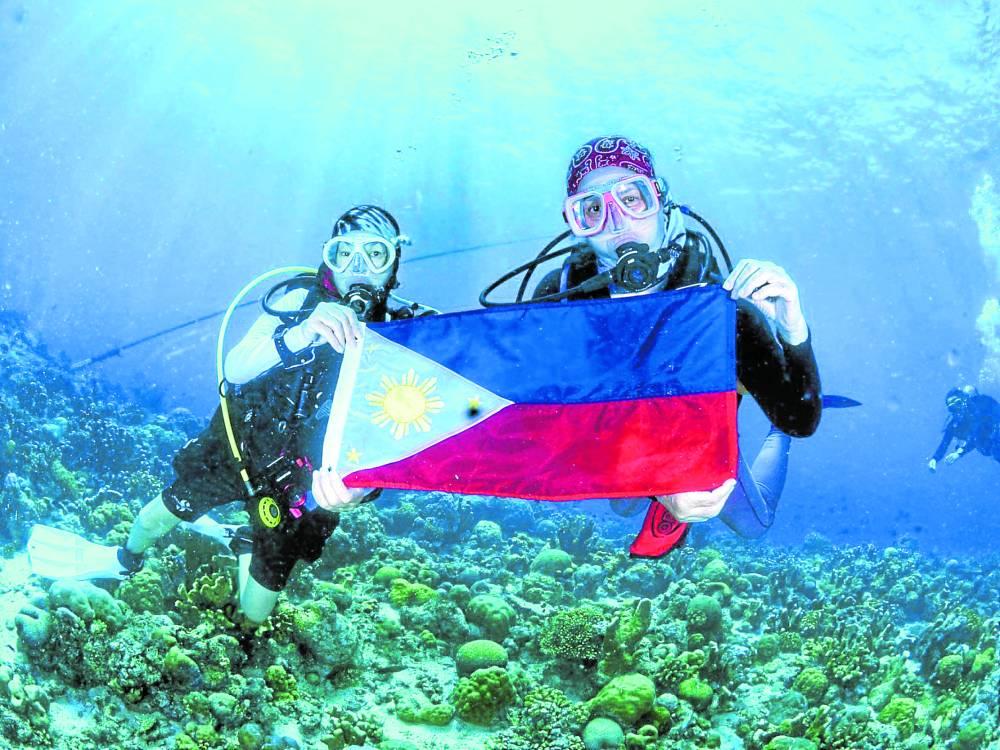 Mawen Ong and the authorhold up a Philippine flag to
mark Independence Day in
the Tubbataha Reefs.