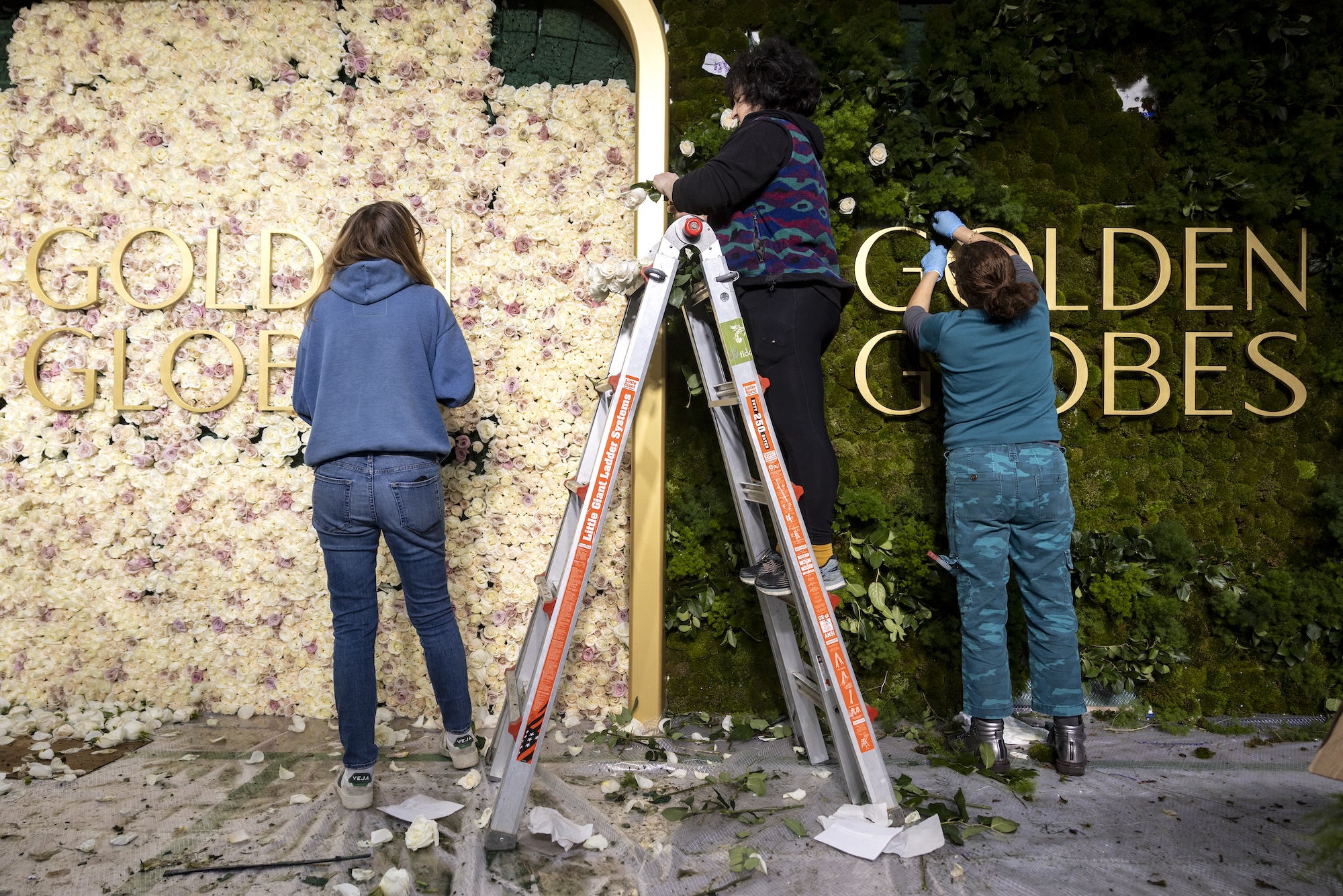 Florists place fresh roses on the backdrop of the red carpet as technicians and workers add the last touches the day before the Golden Globes at Beverly Hilton in Beverly Hills, California, on January 4, 2025. (Photo by ETIENNE LAURENT / AFP)