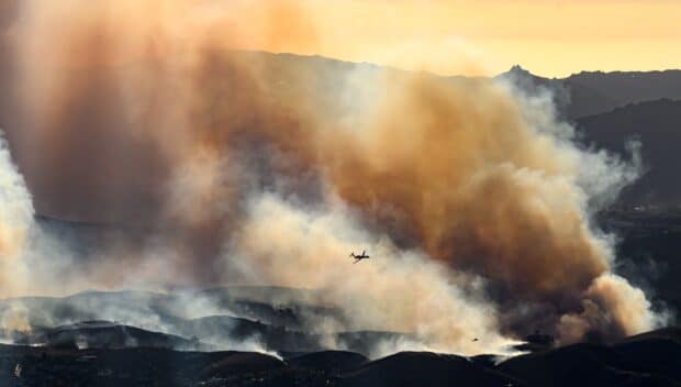 In this aerial view taken from a helicopter, an air tanker prepares to drop fire retardant on the Kenneth fire in the Calabasas area of Los Angeles county, California on January 9, 2025. Massive wildfires that engulfed whole neighborhoods and displaced thousands in Los Angeles remained totally uncontained January 9, 2025, authorities said, as US National Guard soldiers readied to hit the streets to help quell disorder. Swaths of the United States' second-largest city lay in ruins, with smoke blanketing the sky and an acrid smell pervading almost every building. (Photo by JOSH EDELSON / AFP)