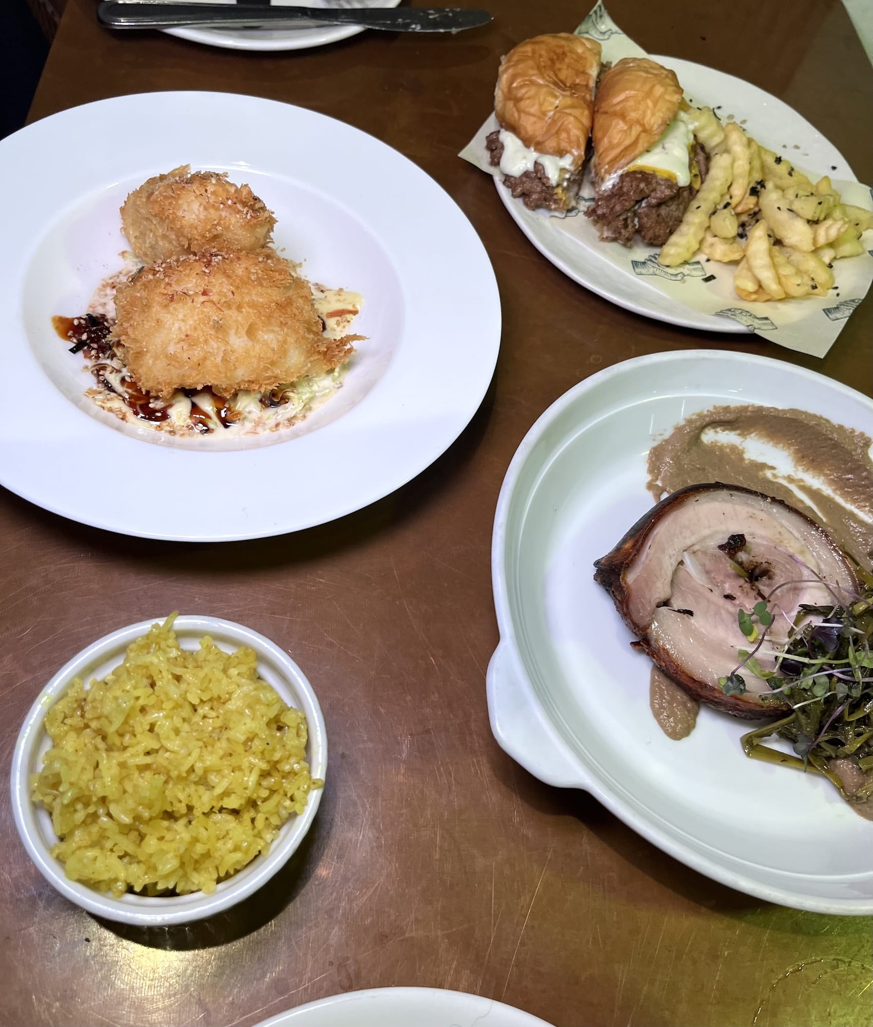 Clockwise from top right: OTP burger and fries, roasted pork belly, turmeric rice, and lapu-lapu katsu