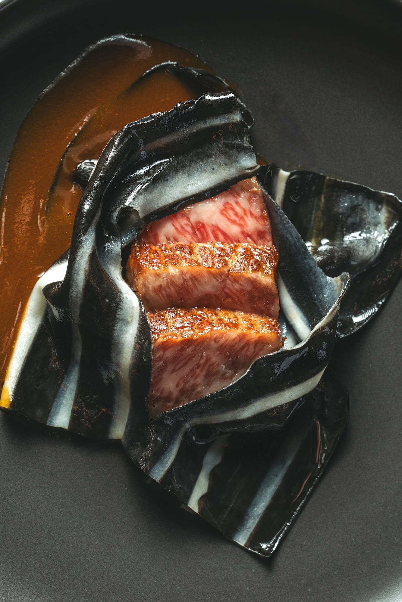 A5 wagyu balbacua (grilled dry-aged A5 wagyu ribeye, black squid ink pasta blanket, kadyos purée, beef tendons demi sauce)